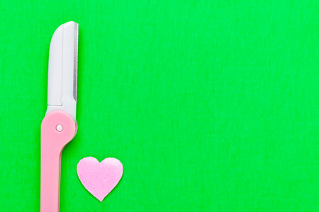 Pink disposable razor blade on green background. Single use razor blade. Disposable shaving razor. body care. Space for text.の写真素材