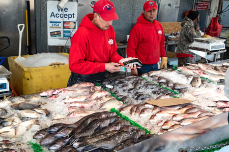 fish seller at a Washington seafood market uses a card reader to pay a customer.