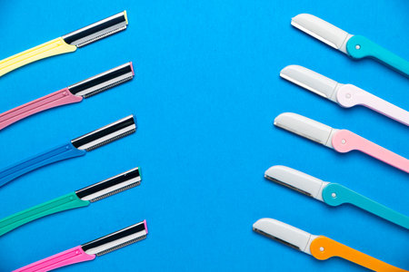 women's razors with plastic handles of different colors on a blue background. Space for text.の写真素材