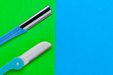 women's razors of different colors for body care on a blue and green background. view from above. Space for textの写真素材