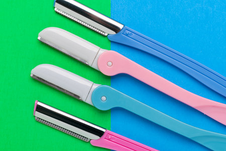 women's razors of different colors for body care on a blue and green background. view from above.の写真素材