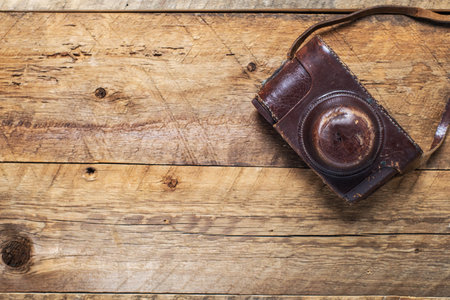 vintage photo camera in a leather case on a textured wooden table. view from above. retro style....