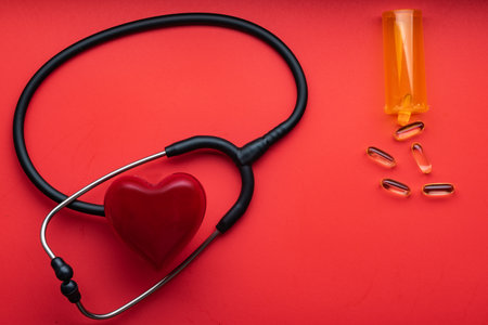 medical stethoscope, red heart and pills on a red background. view from above. Space for text