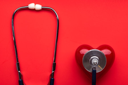Stethoscope and red heart on red background. cardiology concept. Space for text.の写真素材
