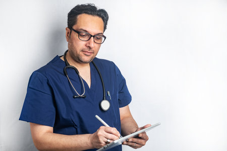 doctor in glasses with a stethoscope writes data into a tablet computer. Space for text.
