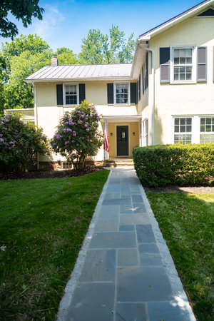Long stone path to the house between bushes and lawn.のeditorial素材