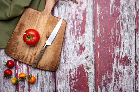 tomatoes on a cutting board with a knife on old painted boards. view from above. Place for text.の写真素材