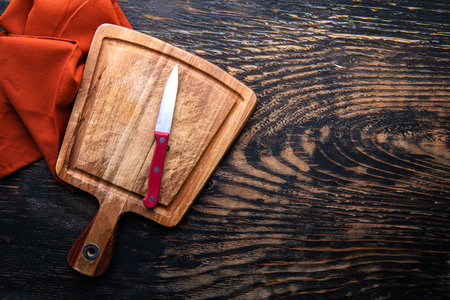 Empty wooden Cutting board, knife and napkin. Table dark background. top view. copyspace.の写真素材