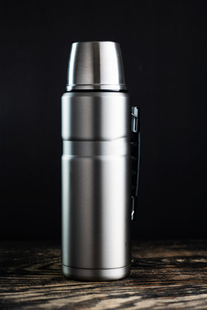 Steel flask on wooden table background.の写真素材