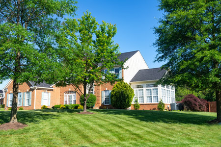 Big luxury house with nicely landscaped front yard and mowed lawn in the suburbs. Summer day, blue sky.のeditorial素材
