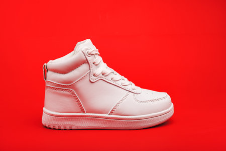 Sports youth shoes on red background close-up. white leather lace-up sneakers.
