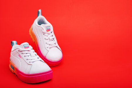 Baby sneakers Puma on a red background. Bright sports walking shoes for girls..のeditorial素材