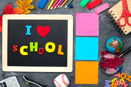School supplies, colored letters, toys and a school board with the inscription I LOVE SCHOOL, Top view. Flat lay on a gray background.の写真素材