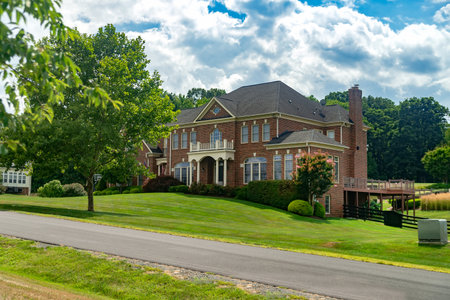 Large country brick house with landscape design near the road.の写真素材