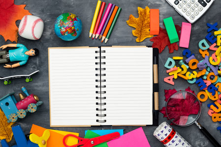 School supplies, colored letters, a toy and an empty school notebook. Space for text. view from above. Flat lay on a gray background.の写真素材