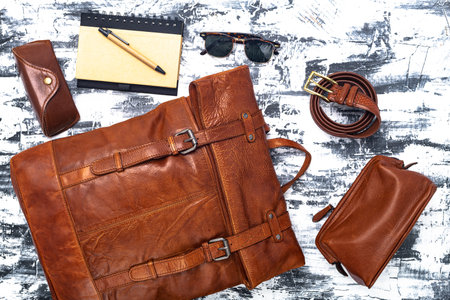 Leather backpack and accessories on a gray table. Stylish brown leather accessories close-up. View...