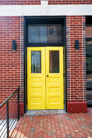 bright yellow front door to a brick house with a brick sidewalk.の写真素材