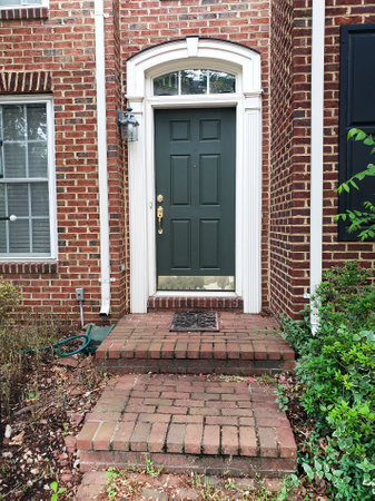 entrance door to a brick house with a sidewalk and a brick porch