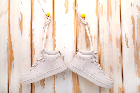 Women's, white, sneakers hang on a nail on a wall of white boards..