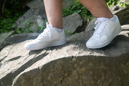 White Nike sneakers on the feet of a hiker climbing rocks