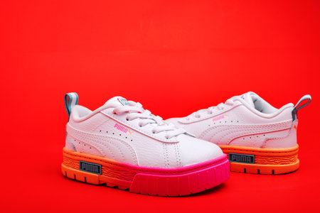 Children's colorful Puma sneakers on a red background.のeditorial素材
