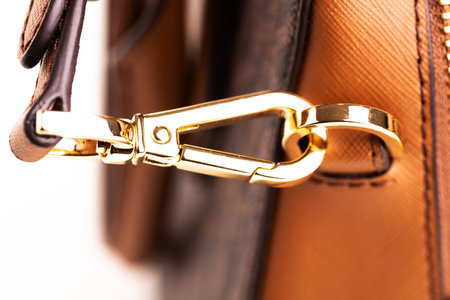Metal gold-plated carabiner and ring-strap on a fashionable women's handbag. Accessory for a woman's...