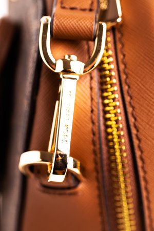 Metal gold-plated carabiner and ring strap on a fashionable women's handbag Michael Kors. Accessory for a woman's look. Close-up.のeditorial素材