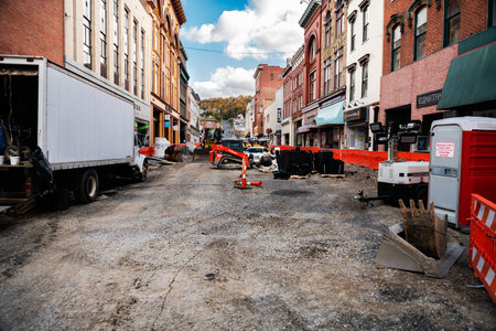 Construction equipment during road works in an urban environment between tall buildings.
