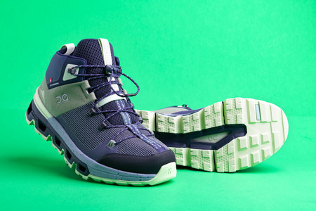 Blue sneakers for sports with laces on green background. Close-up.Space for text