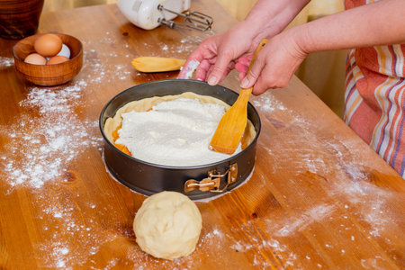 Chef puts cottage cheese in a mold to prepare apricot cheesecake.