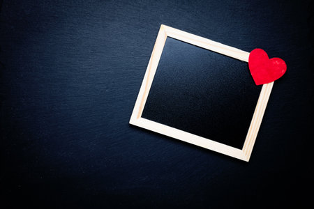 Photo frame and toy heart on a black background. Space for text. Congratulations on Valentine's Day.の写真素材