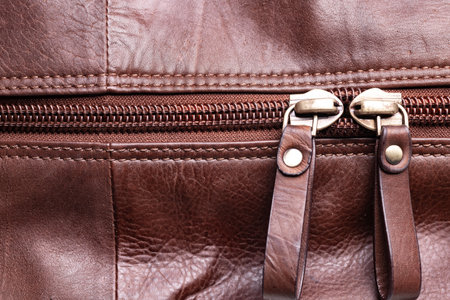 Zipper on a brown leather bag. Textured leather, space for text.