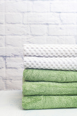 stack clean bath towels colorful cotton terry textile in bathroom white brick background.の写真素材