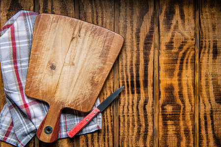 An empty wooden cutting board and napkin on wooden background. Preparation of appliances and ingredients for home cookingの写真素材