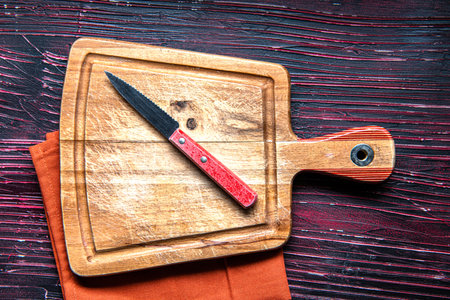 wooden cutting board, knife and napkin on red kitchen table. Space for text.の写真素材