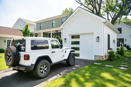 white Jeep Rubicon is parked outside white garage.のeditorial素材