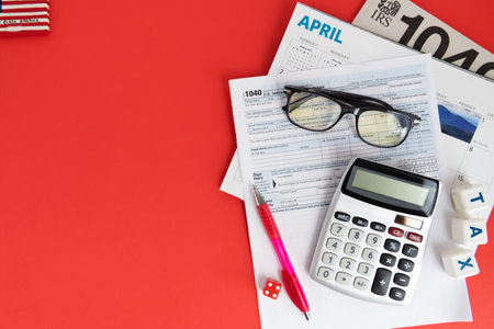 Calendar, calculator and glasses on a red background. US Income Tax Return form Space for text.の写真素材
