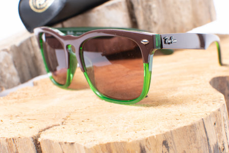 Ray-Ban sunglasses in green frame on wooden background. Popular and fashionable accessoryのeditorial素材