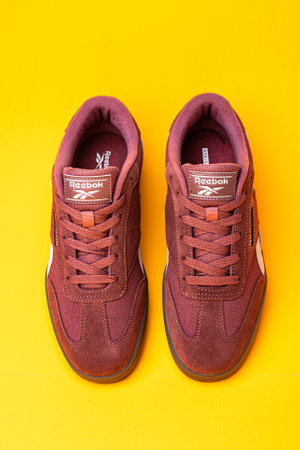 Reebok sports shoes for running and walking. Sneakers made of suede on a yellow background.のeditorial素材