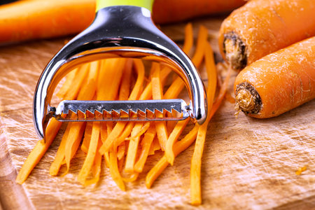 Shredded carrots for salads and other stuff. A tool for chopping vegetables close-up.