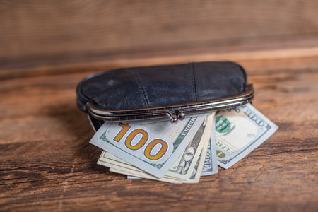 Top view of old black genuine leather wallet with banknotes inside wooden background.の写真素材