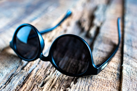 round stylish sunglasses on a textured wooden background.のeditorial素材