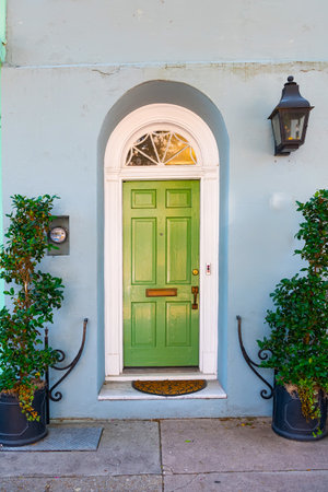 Green wooden front door to a house with a lantern at the entrance. Decorated with flowers.の写真素材