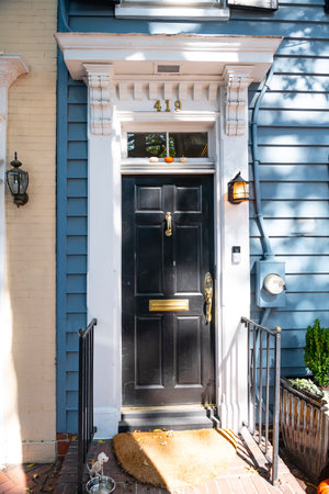 Black wood door to house with porch and metal railing.