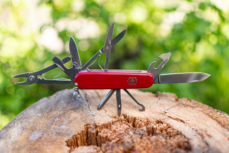 Lying on a wooden stump Victorinox red classic Swiss pocket folding knife with open all tools
