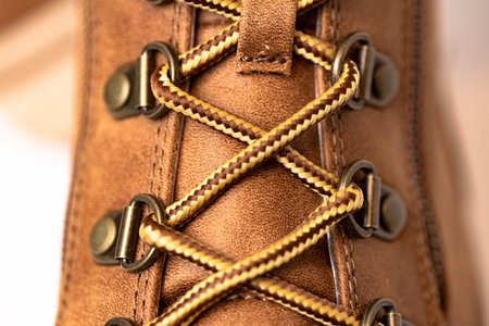 Brown leather boot with metal rivets and laces. Casual urban footwear. Texture of the leather. Macro...
