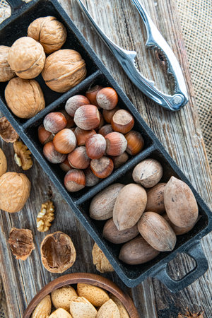 nutcracker for cracking nuts and assorted nuts in a plate on a dark wooden table. Top viewの写真素材