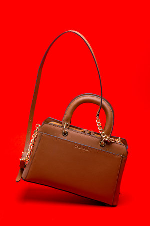 Women's Calvin Klein bag made of brown leather. on a red background.のeditorial素材