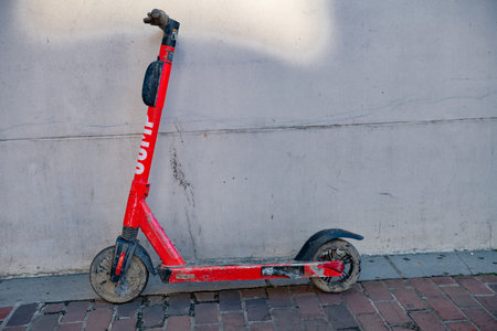 dirty Electric Scooter on the sidewalk is a popular means of transportation.のeditorial素材