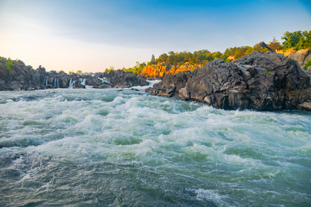 Sunset on a turbulent mountain river with waterfalls and rapids.